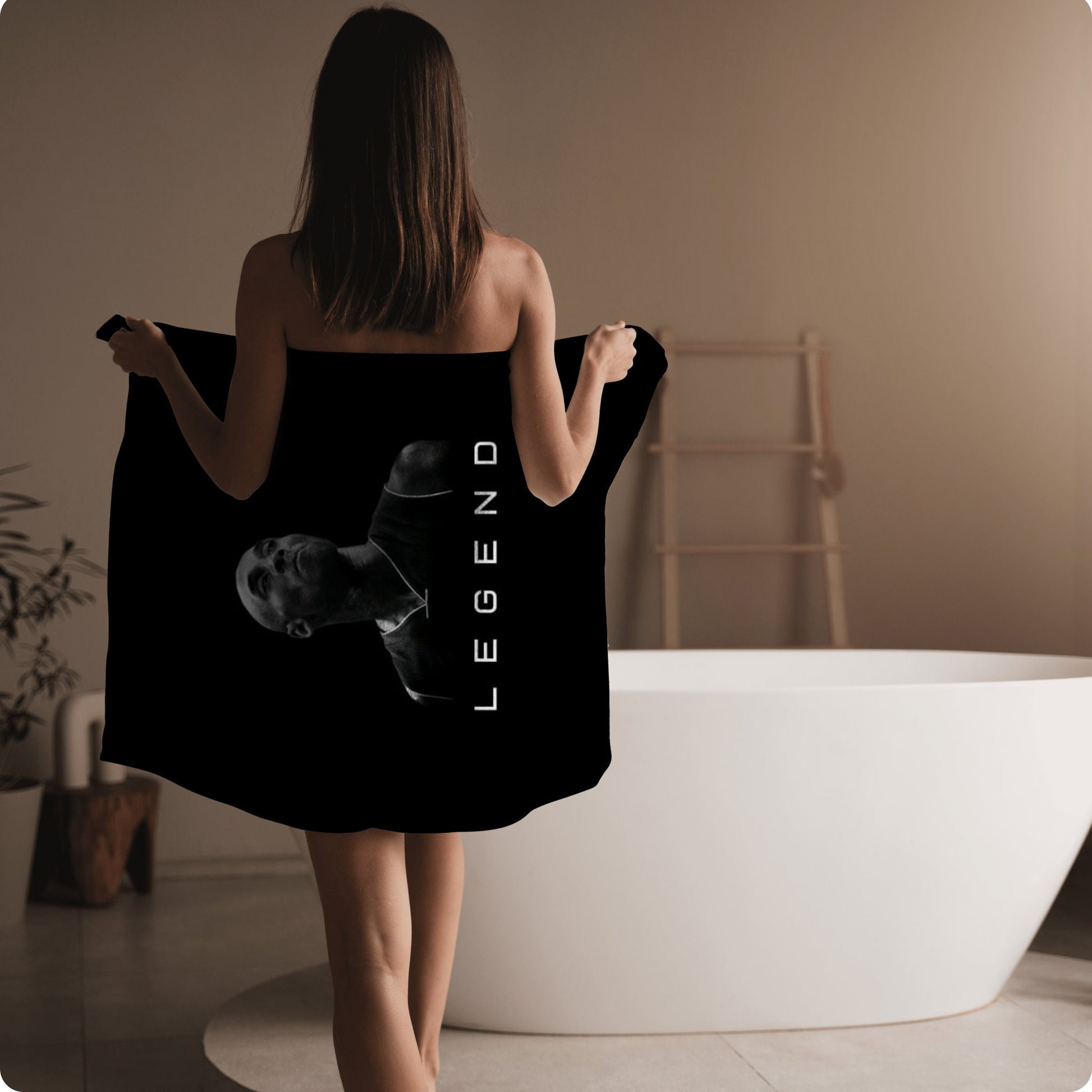 a woman in a black towel is walking towards a bathtub